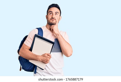 Young handsome man wearing student backpack and notebook serious face thinking about question with hand on chin, thoughtful about confusing idea  Adlı Stok Fotoğraf