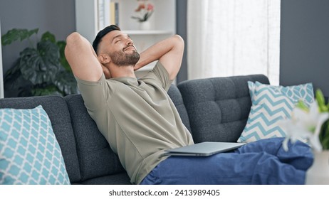 Young hispanic man relaxed with hands on head sitting on sofa at home Arkistovalokuva