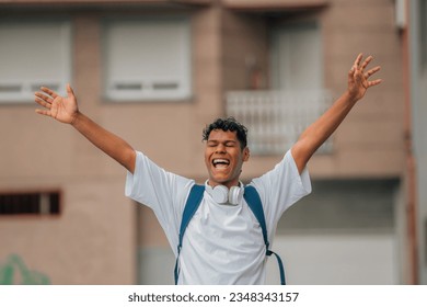 young latin man with arms raised in the street excited with joy 库存照片