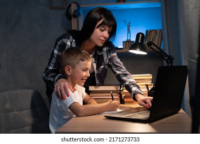夜は自宅で一緒に勉強や学習のためにノートパソコンを使用して若い母親と息子，宿題のためのノートに書く少年，ママ支援の子供，家庭教育のコンセプト。の写真素材