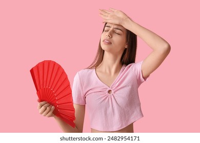 Young pretty woman with red hand fan on pink background 库存照片