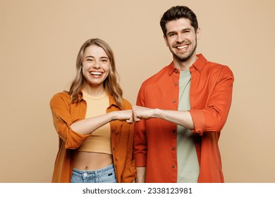 Young smiling happy buddies fun couple two friends family man woman wear casual clothes looking camera giving fist bumo together isolated on pastel plain light beige color background studio portrait Foto stock