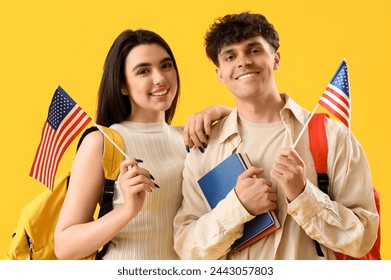 Jóvenes estudiantes con banderas de Estados Unidos sobre fondo amarillo Foto de stock