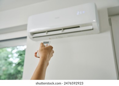 Adjusting air conditioner temperature with remote control. Hand holds remote control and setting comfortable temperature on climate system in apartment: stockfoto