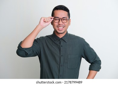 眼鏡のフレームに手を触れて自信を持って微笑むアジア人男性の写真素材