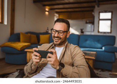 Adult caucasian with eyeglasses man play video games on his phone at home Stockfoto