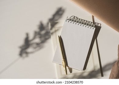 Aesthetic luxury workspace template. Spiral flip notebook with copy space in plant sunlight shadow on white background. Schedule, notes concept for blog, social media, web Stockfoto