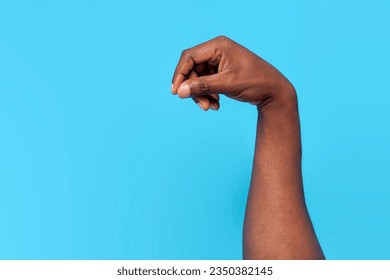 african american male hand pours spices and salts on blue isolated background, the hand holds pinch, close-up Foto stock