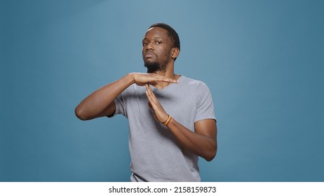 African american man doing timeout gesture with t shape hands, expressing half time and break, declining work. Serious person advertising pause symbol with palms, stop and refuse control. Arkistovalokuva