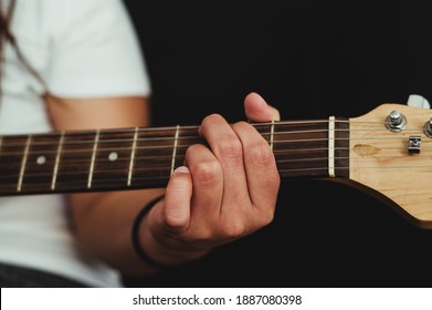 エレキギターの匿名の手、黒い背景にエレキギターを弾く匿名の人の手の接写の写真素材