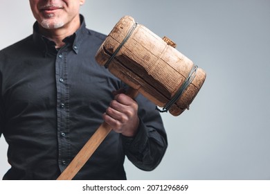 Anonymous man holding a large wooden mallet with a smile in a concept of authority, boss, dominance and determination in a close up on his hand 库存照片