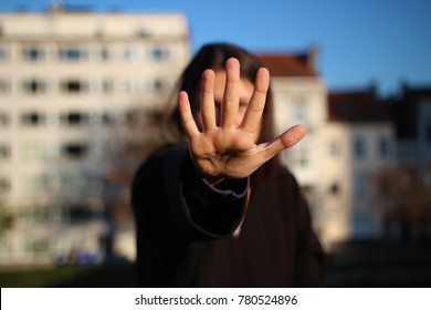 An anonymous, young, beautiful woman, holding her streched out hand in front of her face. The strong bokeh blurs out everything behind the palm. Concept of saying Stop, woman power, sexual harassment. : photo de stock