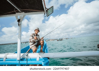angler sitting at the end of the boat with thumbs up on a small fishing boat at sea Foto stock