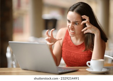 バーテラスでノートパソコンの問題を抱えている怒った女性 の写真素材