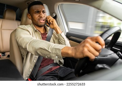  車を運転している間に電話で戦う怒ったアフリカの若い男、彼の携帯電話を使用して不注意なドライバー、車の中で右を表示しますの写真素材