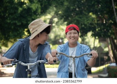 Asian boy is spending his free times by riding bike with his friend in his school park at the weekend, soft and selective focus. Stock-foto