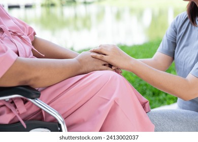 Asian careful caregiver or nurse taking care of the patient in a wheelchair.  Concept of a happy retirement with care from a caregiver and Savings and senior health insurance, encourage the patient 库存照片