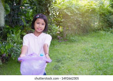 Asian child girl holding a plastic bag with a plastic bottle inside the bag over nature background. Concept of Recycling and Utilization of Plastic Waste. – Ảnh có sẵn