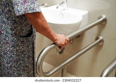 アジアの高齢者の高齢女性の患者は、トイレのトイレのサポートレールを使用し、手摺安全グラブバー、介護病院のセキュリティ。の写真素材