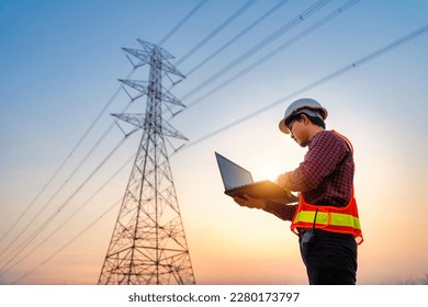アジアの電気技術者が発電所のノートパソコンで位置を確認し、作業を計画します。高圧電柱の製造。の写真素材
