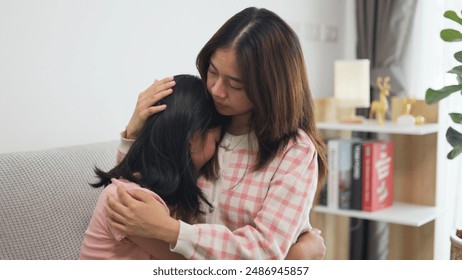 Asian girls comforting her crying sister, hugging her, and whispering words of support, closeup. Asian girls embrace female kid, touching her head, and saying something Foto Stock