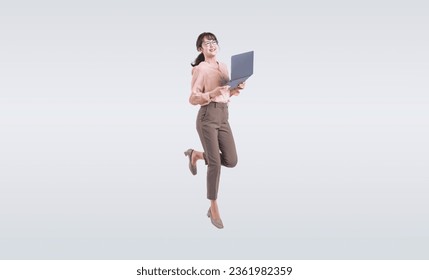 Asian middle-aged business woman wearing a suit using a laptop PC while jumping energetically Foto stock