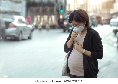 PM2.5のダストマスクを着用し、路上で咳をするアジアの妊娠中の女性。 マスクを着用すると、汚染、スモッグやウイルス、大気汚染、頭痛の窒息から保護します。都市の大気汚染。の写真素材