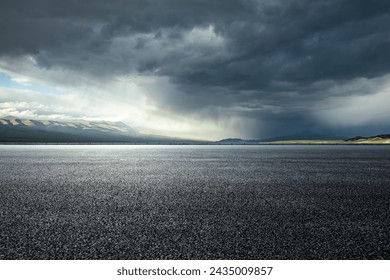 大雨の前にアスファルトの道路や暗い雲と山の写真素材