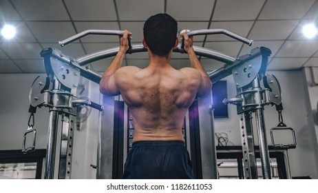 Athlete muscular bodybuilder training on simulator in the gym, strong male. Stock Photo