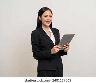 Attractive elegant young asian business woman using digital tablet standing on isolated background. Happy young latin female formal black suit holding tablet gadget working service with customer Stock-foto