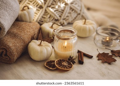 Autumn composition with aromatic candle, dry citrus, cinnamon, anise. Aromatherapy on a grey fall morning, atmosphere of cosiness and relax. Wooden background, pumpkin as decor Foto Stock