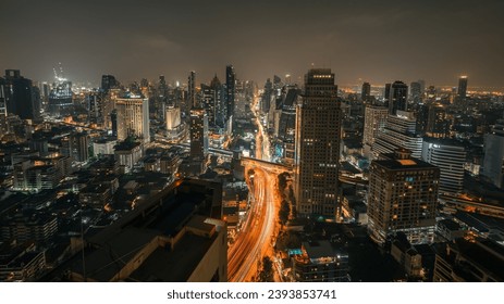 タイバンコク – 2023年3月15日：近代的な都市の夜の街の景観のスカイラインパノラマと高速道路の輸送ライトトレイル。ライトアップされた高層ビルや移動車両が道路を照らします。高角度のエディトリアル写真素材