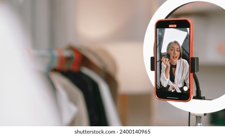 Back view influencer shoot live with smartphpone streaming using vlog video review makeup prim social media or blog. Girl with cosmetics studio lighting for marketing recording session online. Stock Photo