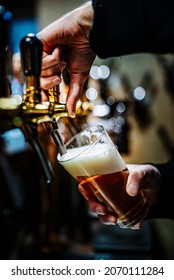 バーやパブで出されるグラスに生ビールを注ぐビールタップのバーテンダーの手の写真素材