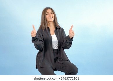 Beautiful Arab woman happy looking excited thumbs up on solid blue background. Professional Arabian or Indian lady attractive long hair wearing formals Stock-foto