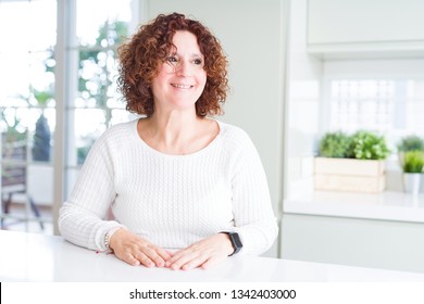 Beautiful senior woman wearing white sweater at home looking away to side with smile on face, natural expression. Laughing confident. Stock-foto