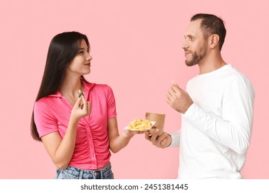 Beautiful young couple with french fries on pink background Stock-foto