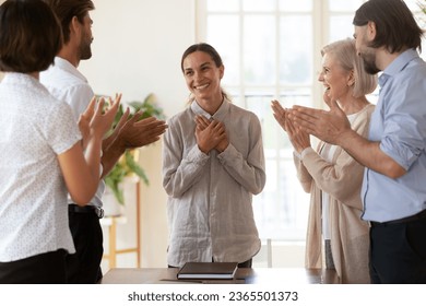 Best employee of month promoted successful female worker or newcomer receiving appreciation or encouragement from diverse staff clap hands her while she folded arms over chest feels flattered grateful Arkistovalokuva