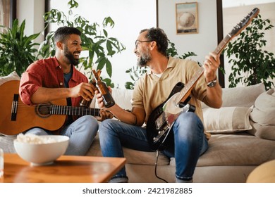 Best friends, musician jamming together. Playing music on guitar together, having beer and fun. Concept of male friendship, bromance. Stockfotó