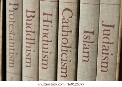 Book spines listing major world religions - Judaism, Islam, Catholicism, Hinduism, Buddhism and Protestantism. The focus is on the word, Catholicism. Stock Photo