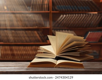 Books on wooden table against full shelves in library स्टॉक फ़ोटो