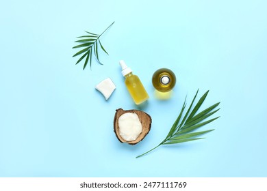 Bottles of coconut cosmetic oil with plant leaves on blue background: zdjęcie stockowe