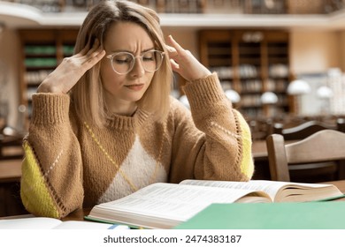 Blonde young woman studying in the library 庫存照片