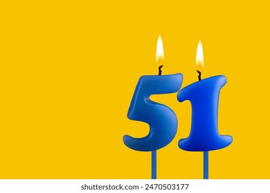 노란색 배경에 파란색 생일 촛불 - 번호 51 스톡 사진