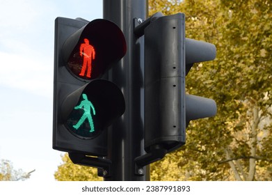 Señales rotas de semáforo, que muestran al mismo tiempo símbolos de hombres peatones caminando y parados, en los árboles y en el fondo del cielo. Foto de stock