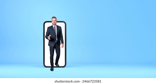 Businessman in a suit stepping out of a giant smartphone screen against a blue background. Concept of digital technology and innovation: stockfoto
