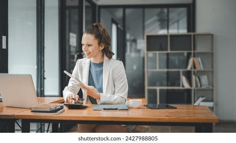 Concept d'analyse d'entreprise, femme d'affaires joyeuse organisant son emploi du temps avec un ordinateur portable assis à un bureau en bois avec un ordinateur portable dans un bureau contemporain.

 : photo de stock