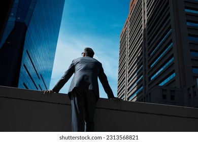Business, man and thinking at city on rooftop about career or future with goal in company. Professional, person and skyscraper on roof is standing with vision or hope for decision as leader at work.: stockfoto