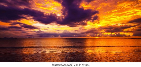 嵐の後の穏やかな海 – 熱帯の島の壮大な金色の黄色い夕日の嵐の後の雨雲の反射と滑らかな海 – タイ、コーランタ（海の中心に焦点）の写真素材