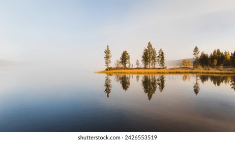 Calm water reflects trees during autumn morning in the lapland nature, Finland Foto stock